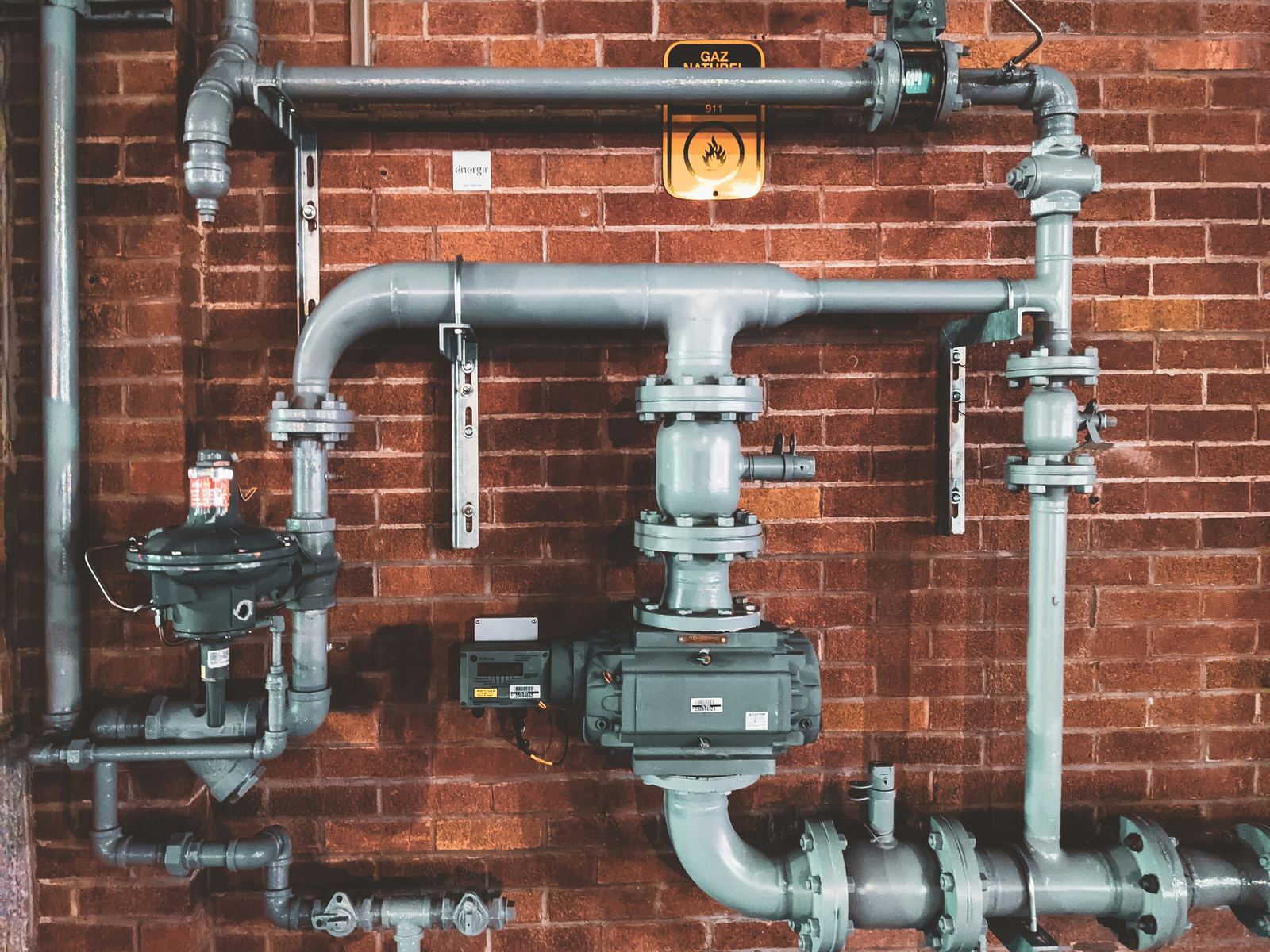 Industrial gas pipes and valves mounted on a brick wall