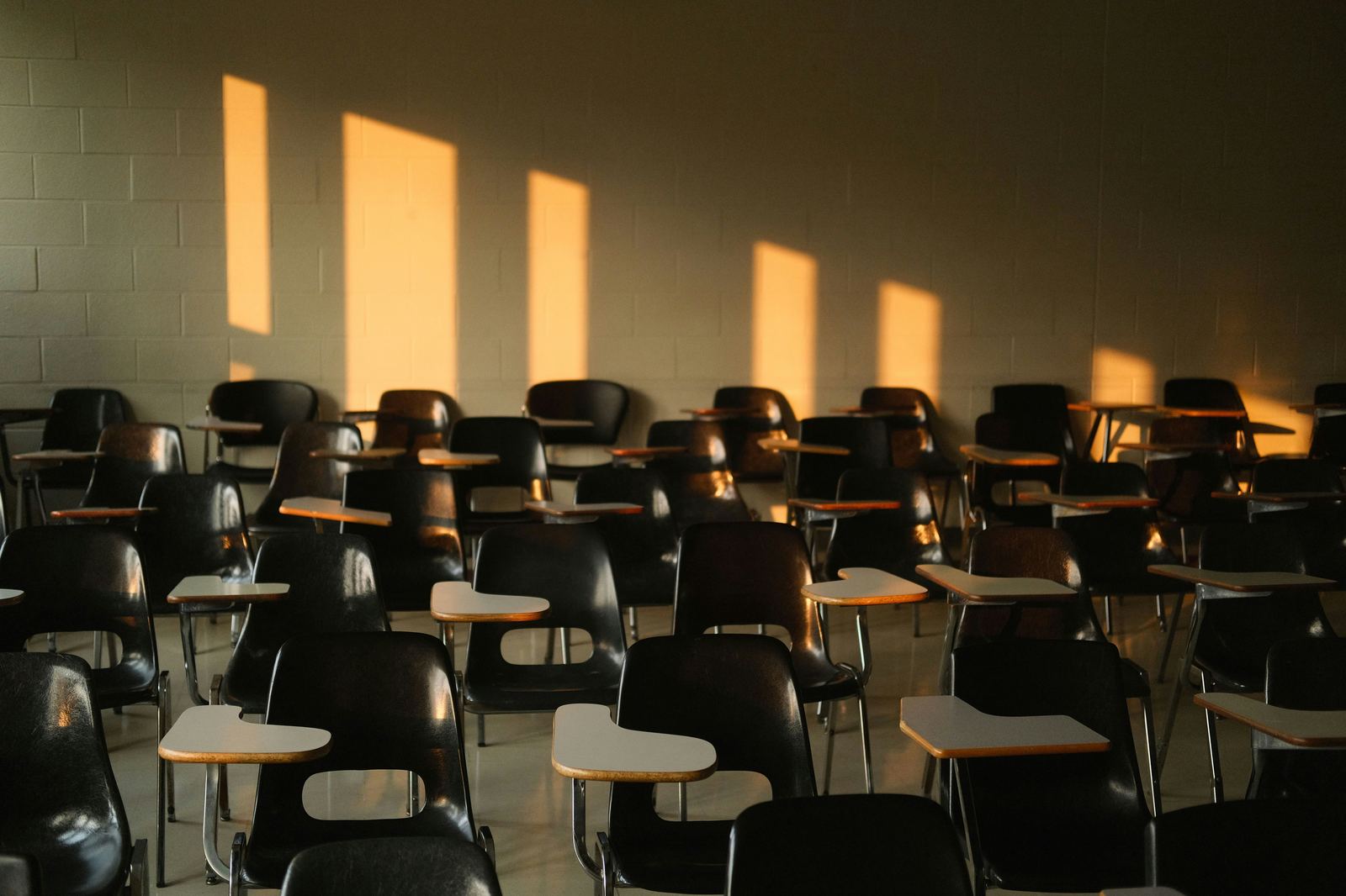 Empty classroom with rows of desks and sunlight casting shadows