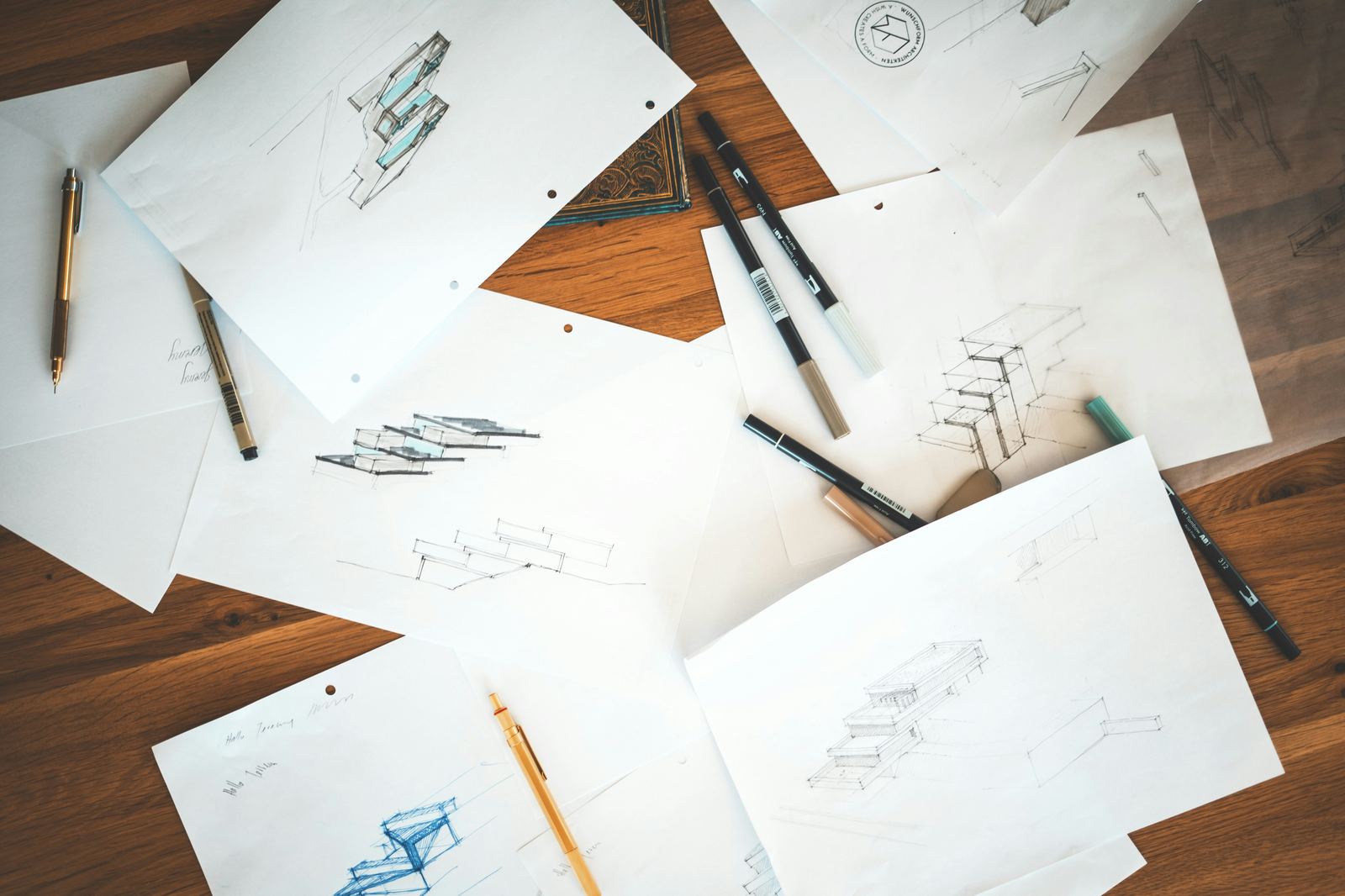 Pencil sketches and design papers scattered on a wooden desk