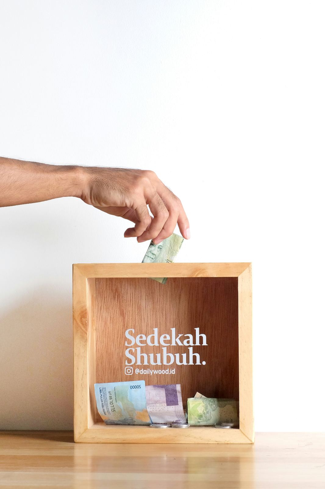 Hand placing a donation into a wooden collection box